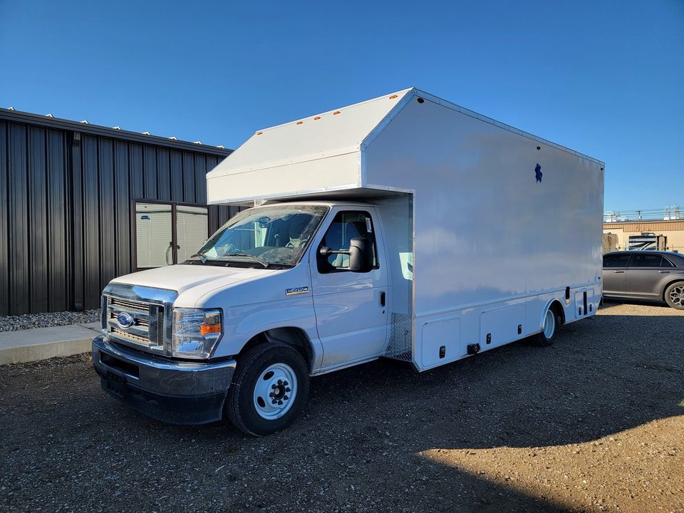 White mobile treatment unit on a Ford E-450 cutaway, front three-quarter, outside, blue sky
