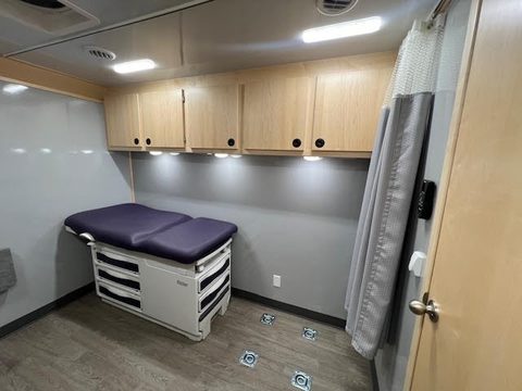 Exam room with exam table, privacy curtain and maple cabinets