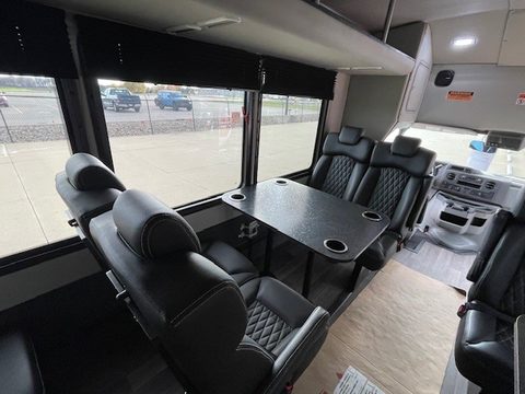 Bus interior: black captain chairs facing pedestal tables