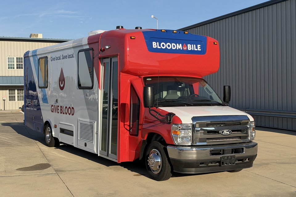 Bloodmobile on a Ford E-450 cutaway, front three-quarter, outside the HLE plant