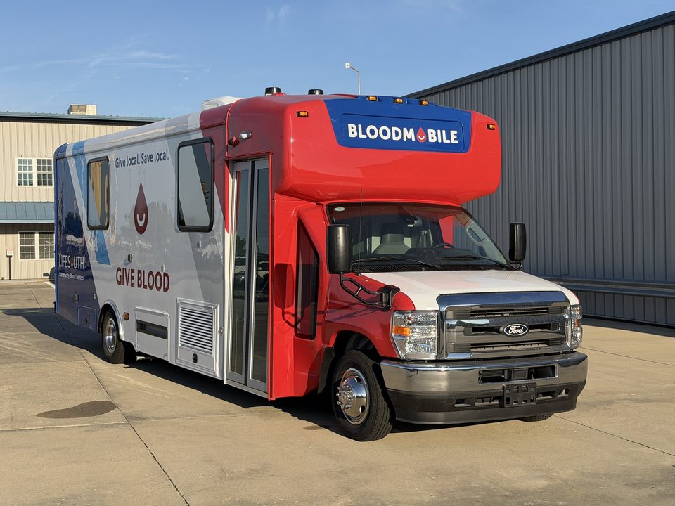 Bloodmobile on a Ford E-450 cutaway, front three-quarter, outside the HLE plant