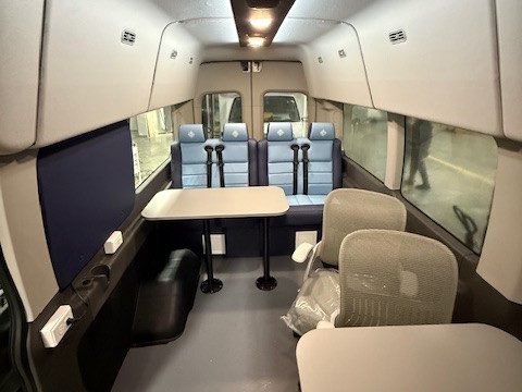 Van interior: forward-facing seats, pedestal tables and task chairs