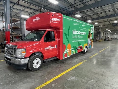 WIC Grocery Mobile Market on a Ford E-Series cutaway, red cab and green wrap, front three-quarter, in the HLE plant