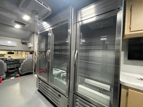 Glass-door coolers and a counter with cabinets inside the mobile market