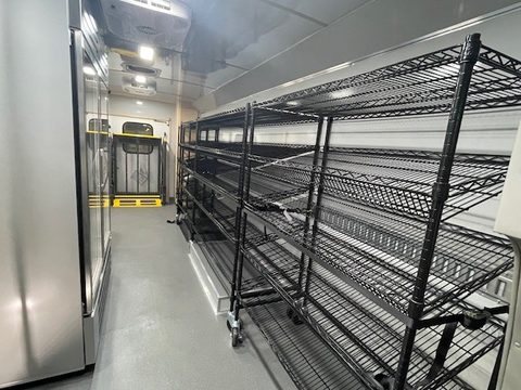 Mobile market interior: wire shelving along the wall, glass-door cooler
