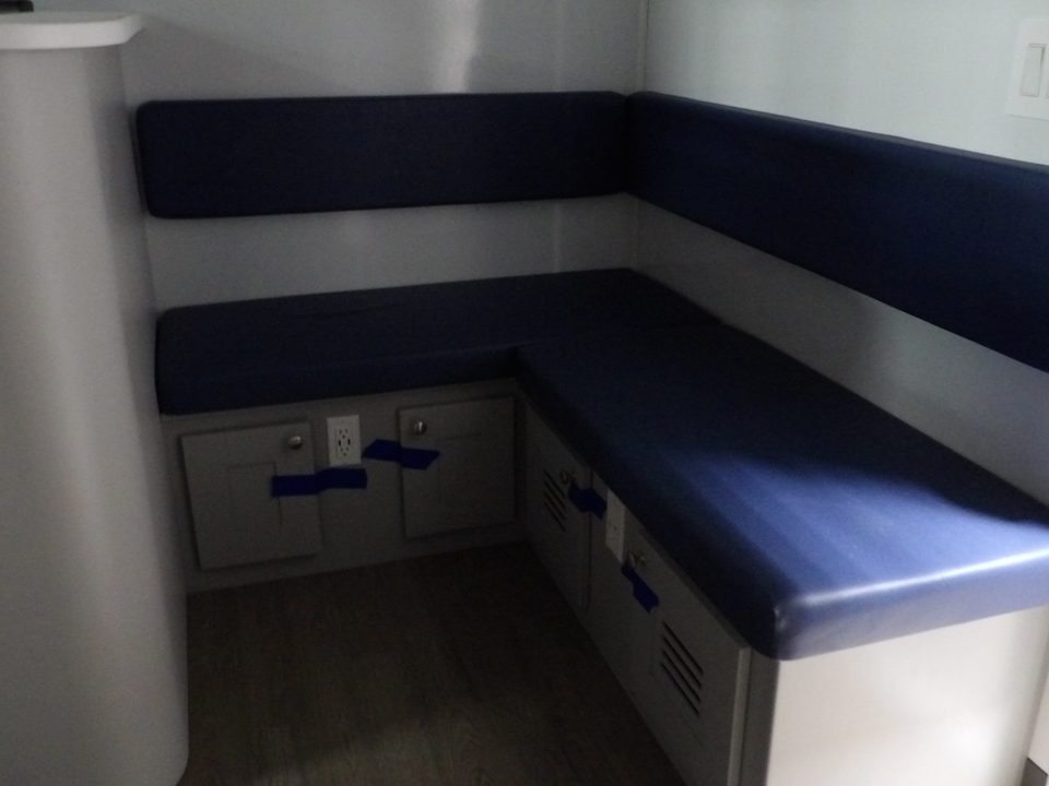 Waiting area: navy upholstered L-shaped bench with storage below