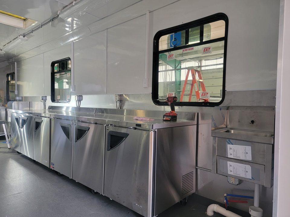 Undercounter refrigeration and stainless prep counters along the windows