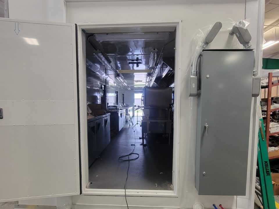 Container end with entry door open, looking down the length of the kitchen