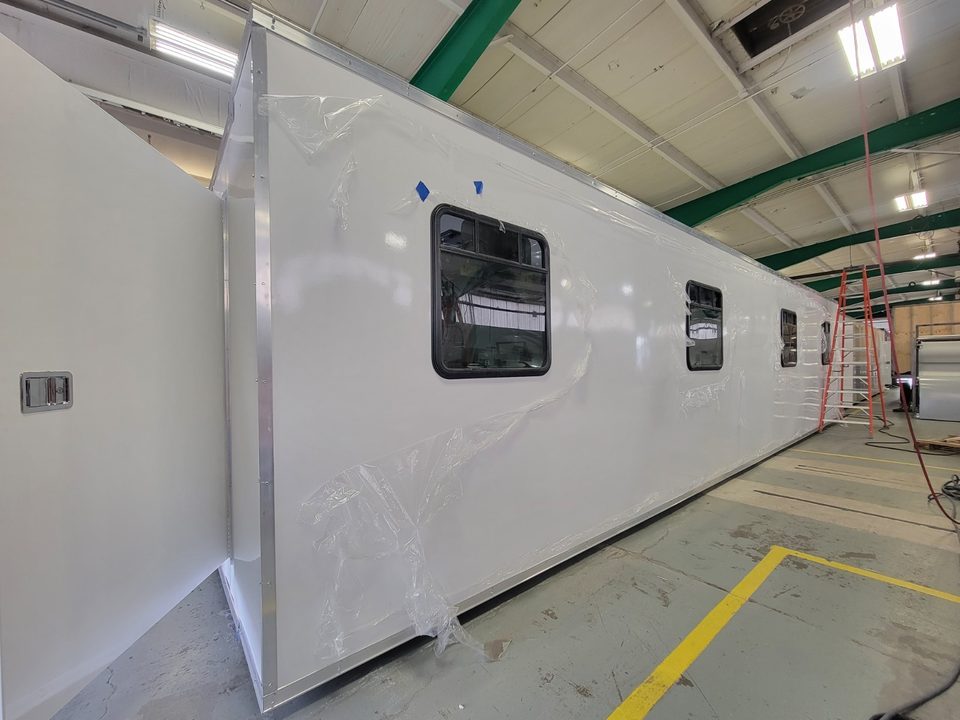 Long white kitchen container with windows, protective film still on, inside the HLE plant