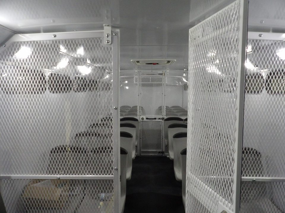 Aisle between steel-mesh compartment walls inside the prisoner transport