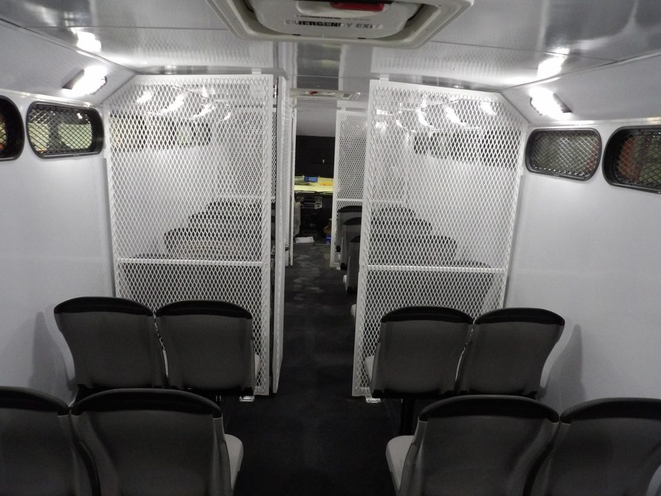 Prisoner transport interior looking aft: steel-mesh compartments, molded seats, emergency exit hatch