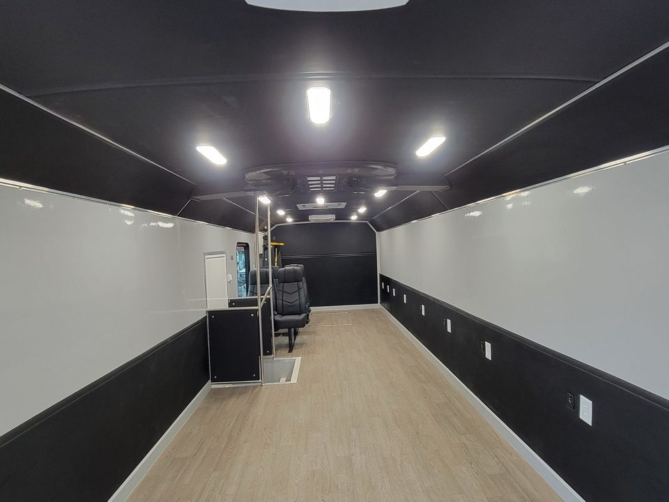 Mobile voting unit interior: open floor, dark walls, wood-look floor