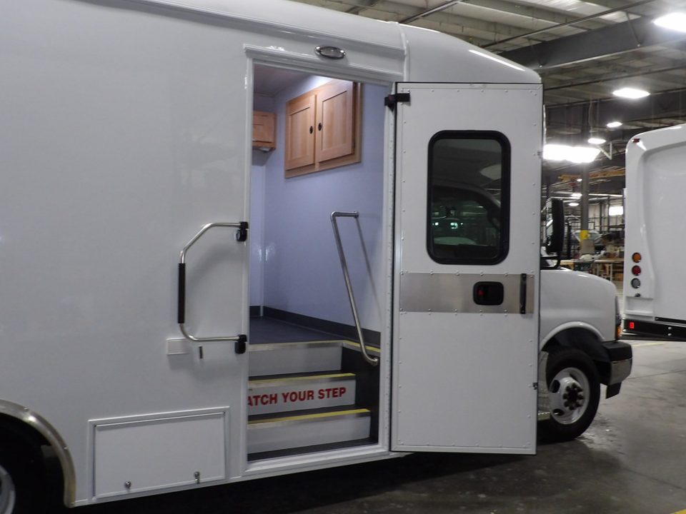 Curbside entry door open with grab rail and steps marked watch your step