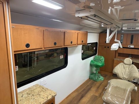 Dental operatory with overhead light, dental chair and cherry cabinets