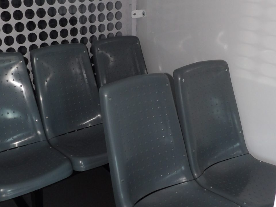 Grey molded inmate seats inside a perforated-steel cell