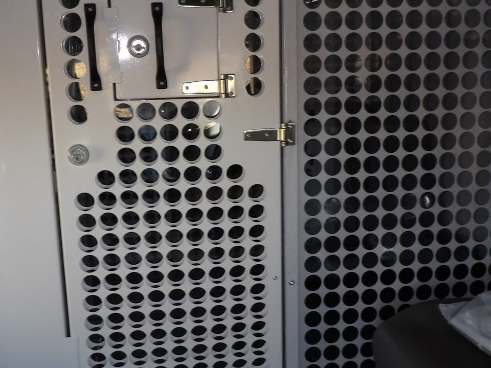 Perforated-steel security partition with locking cell door