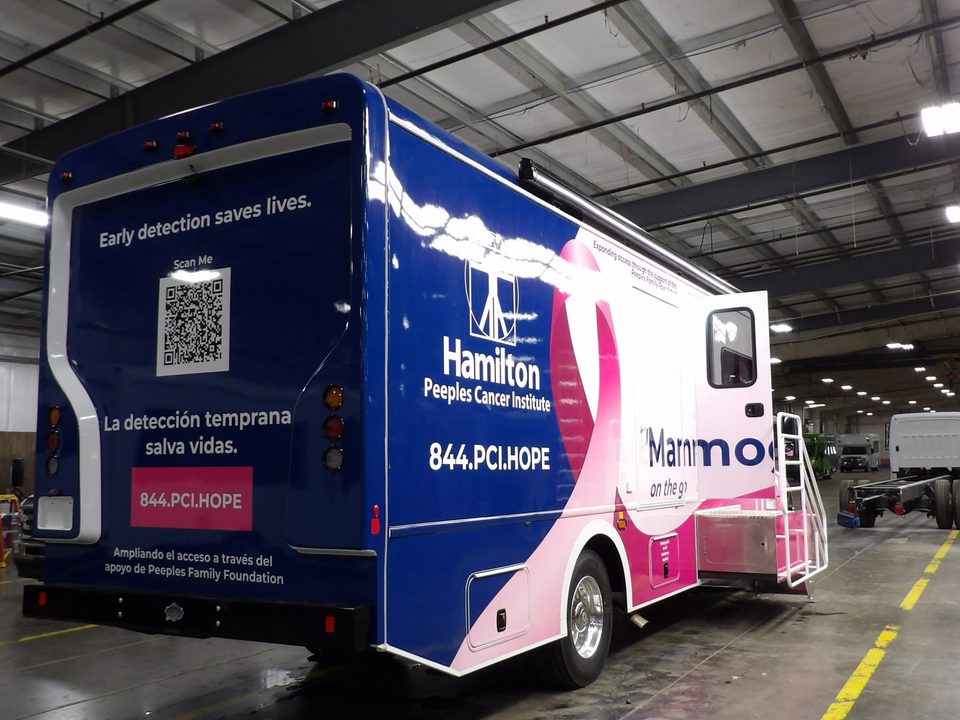 Mammography unit, rear three-quarter, navy wrap with QR code and Spanish message
