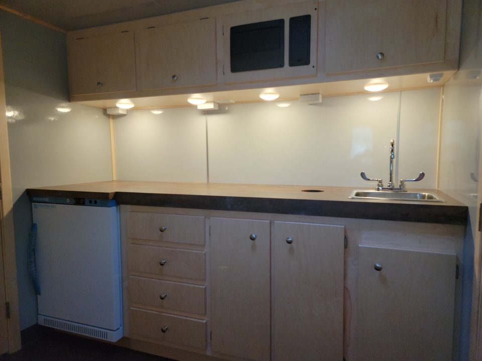 Counter with sink, refrigerator and maple cabinets inside the health van