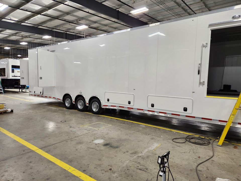 White triple-axle gooseneck trailer in the HLE plant, side