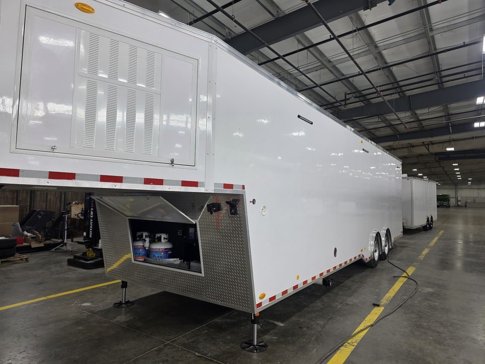 Gooseneck trailer front with the generator and propane compartment open