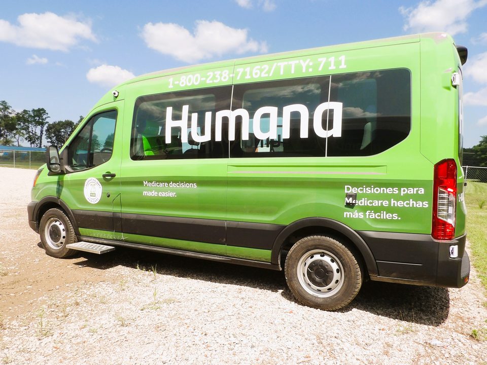 Green Humana outreach van on a Ford Transit, driver side with the awning, outside under blue sky