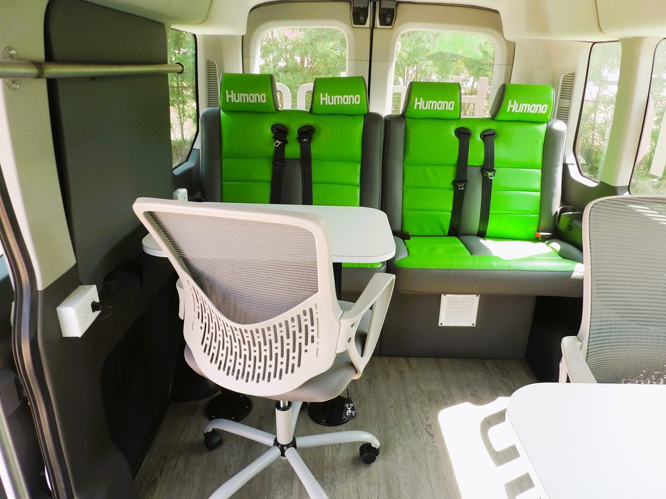 Van interior: green bench seats, task chair and fold-down table