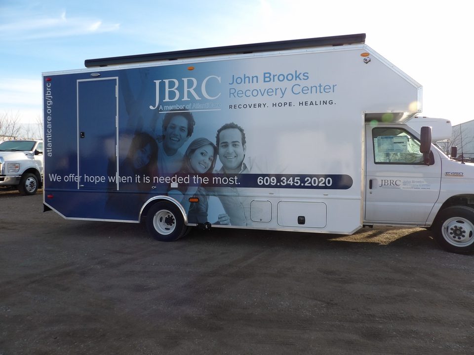 Mobile recovery unit, driver side, full-length wrap with the entry door and awning