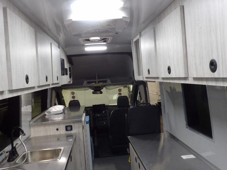 Lab van interior looking forward: overhead cabinets, stainless counter with sink