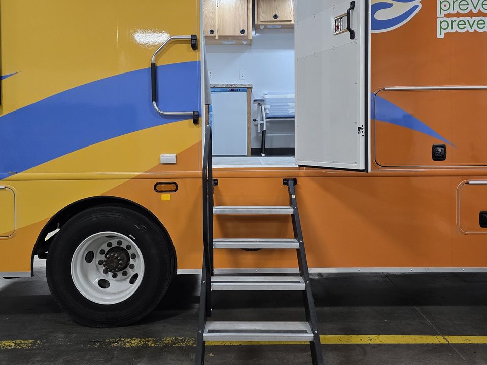 Curbside entry door open with fold-down steps on the mobile health clinic