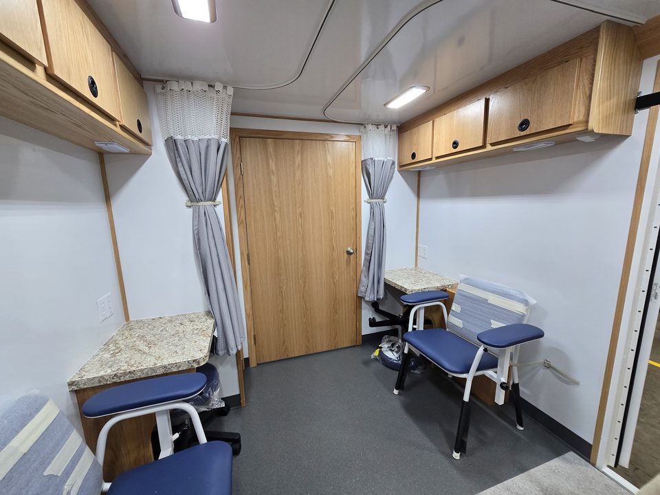 Exam area with privacy curtains, patient chairs and side counters