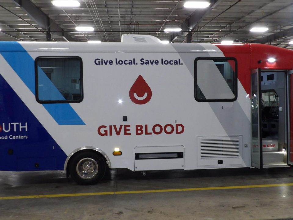 Bloodmobile, passenger side, wrapped Give local Save local, entry door open, in the HLE plant