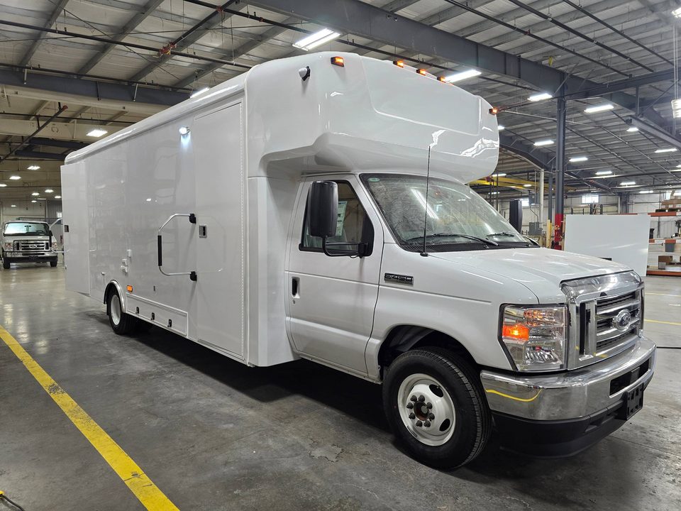 White mobile outreach unit on a Ford E-450 cutaway, front three-quarter, in the HLE plant