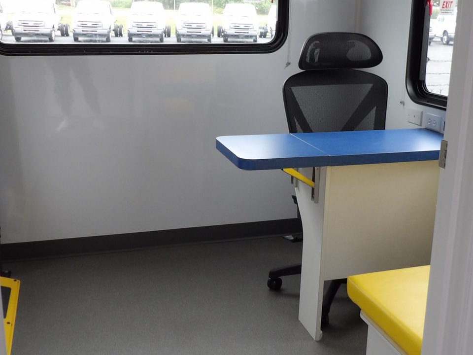 Outreach unit workstation with blue desktop and office chair at the window