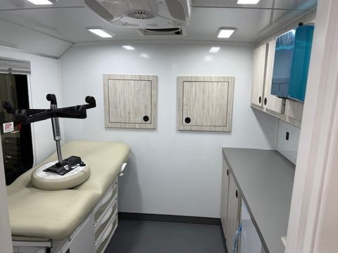 Exam room with exam table, cabinets and a wall display