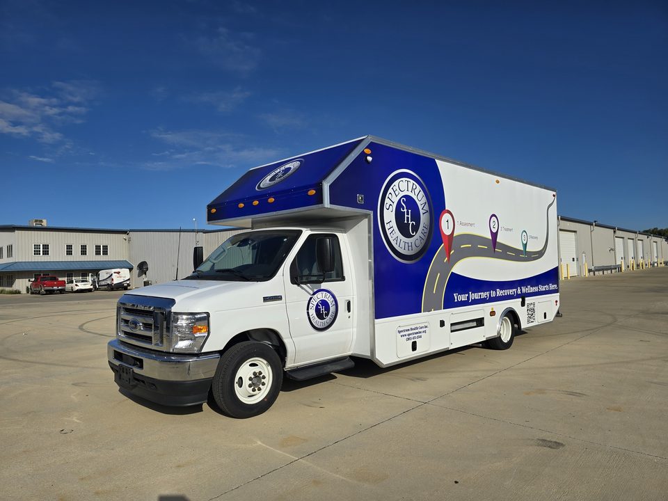 Mobile recovery unit on a Ford E-Series cutaway, blue and white wrap reading Your Journey to Recovery, front three-quarter