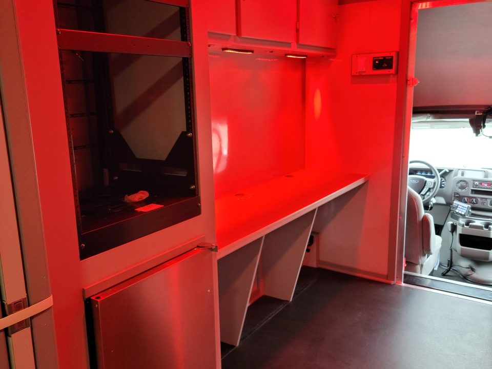 Interior under red night lighting, equipment cabinet and counter