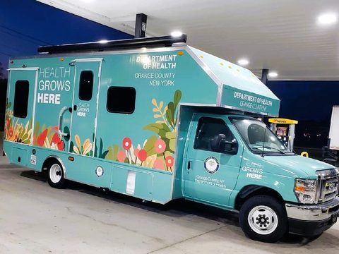 Mobile health unit outside at dusk, front three-quarter, wrapped