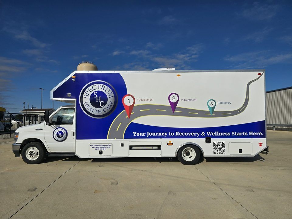 Mobile recovery unit on a Ford E-450 cutaway, Spectrum Health Care road-map wrap, driver side, blue sky