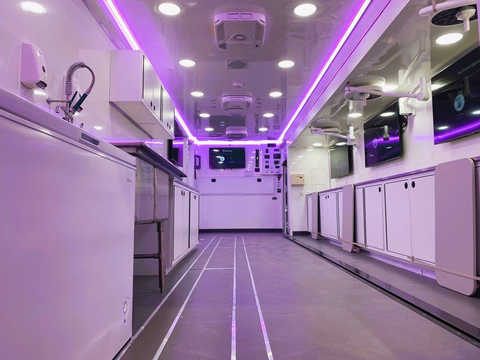 Lab trailer interior with stainless counters under purple LED cove lighting