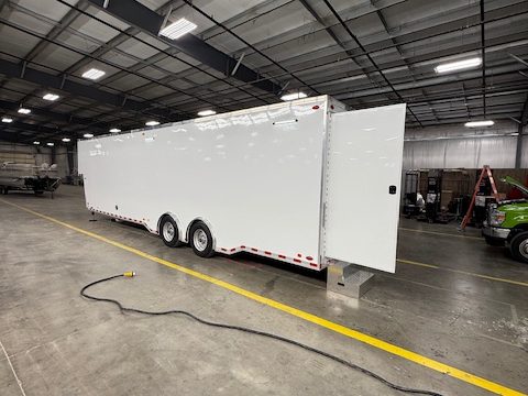 White tandem-axle gooseneck trailer in the HLE plant, side door open