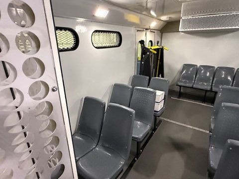 Grey molded seats behind a perforated-steel partition