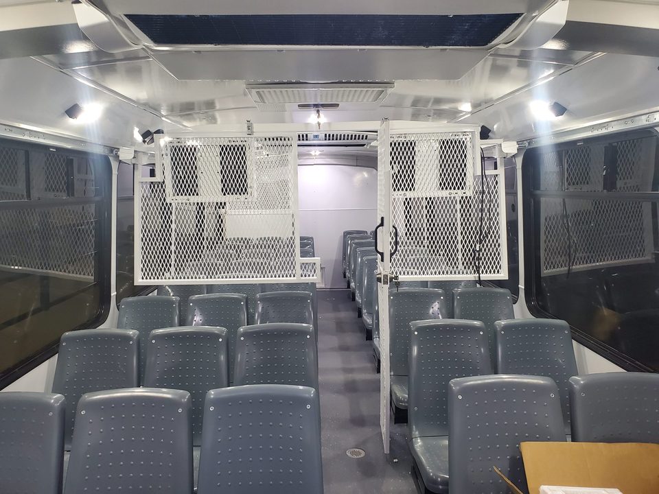 Prisoner transport interior: steel-mesh compartments, molded seats, officer aisle
