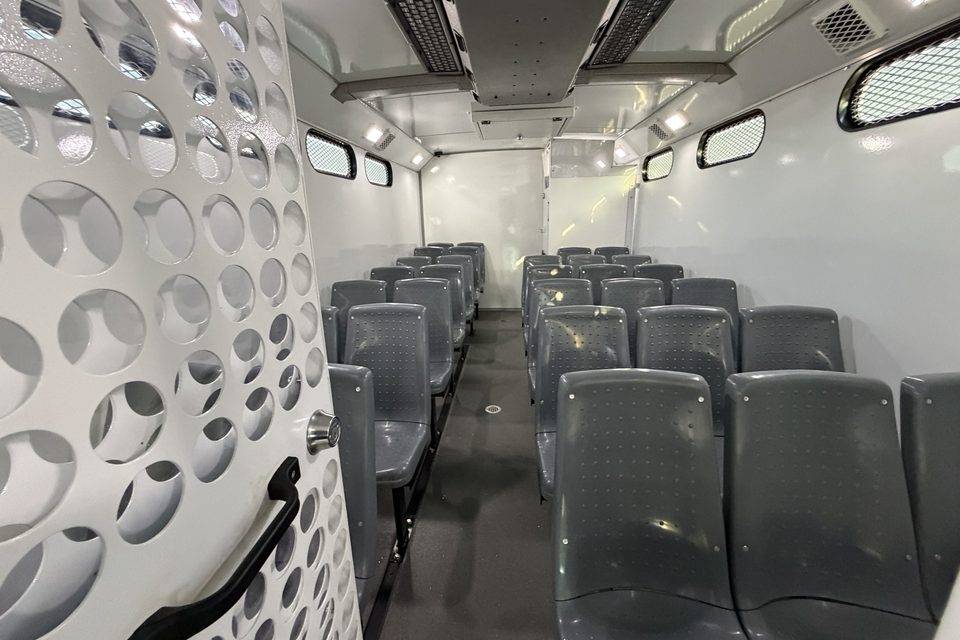 Prisoner transport interior: molded seats, perforated steel partitions, secure restroom at the rear