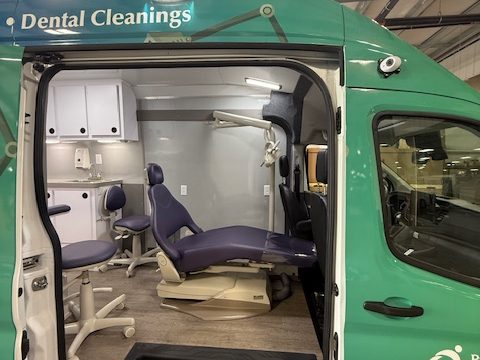 Side door open on the dental van showing the dental chair