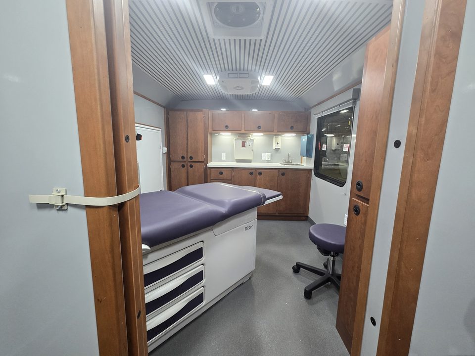 Exam room with exam table, stool and wood cabinetry