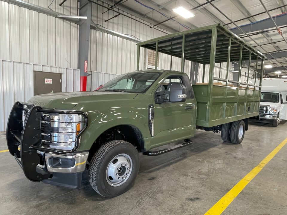 Olive-green safari truck (open-air passenger truck) on a Ford F-350 chassis cab, front three-quarter, in the HLE plant