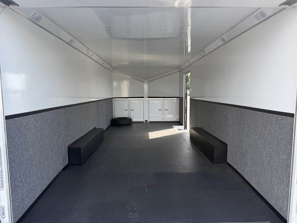 Enclosed trailer interior: white walls, bench boxes, cabinets at the front