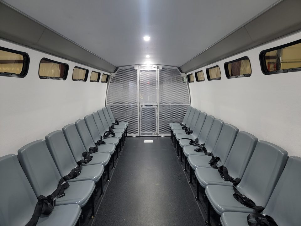 Prisoner transport interior: molded seats both sides of the aisle, mesh partition at the rear