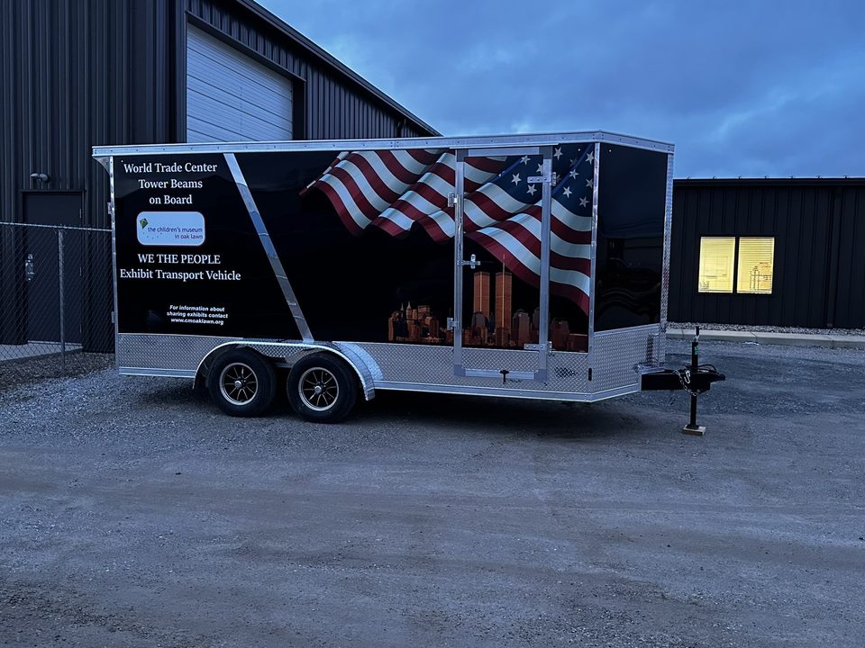 Enclosed trailer wrapped with a flag and skyline graphic for a museum exhibit, outside