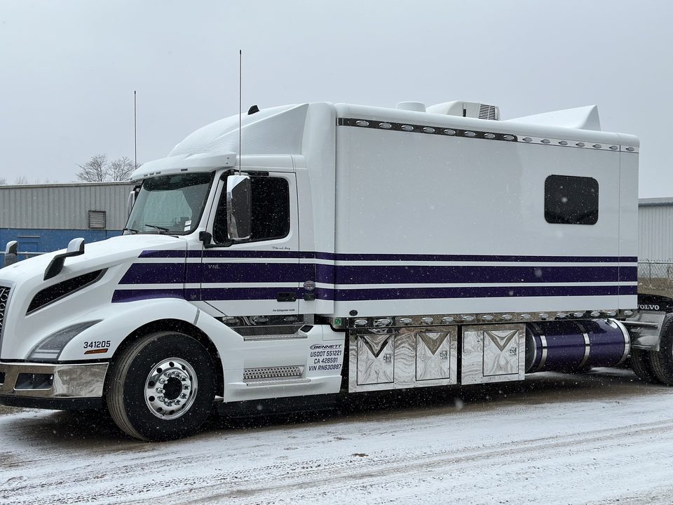 White sleeper tractor with a purple stripe wrap, side, in snow